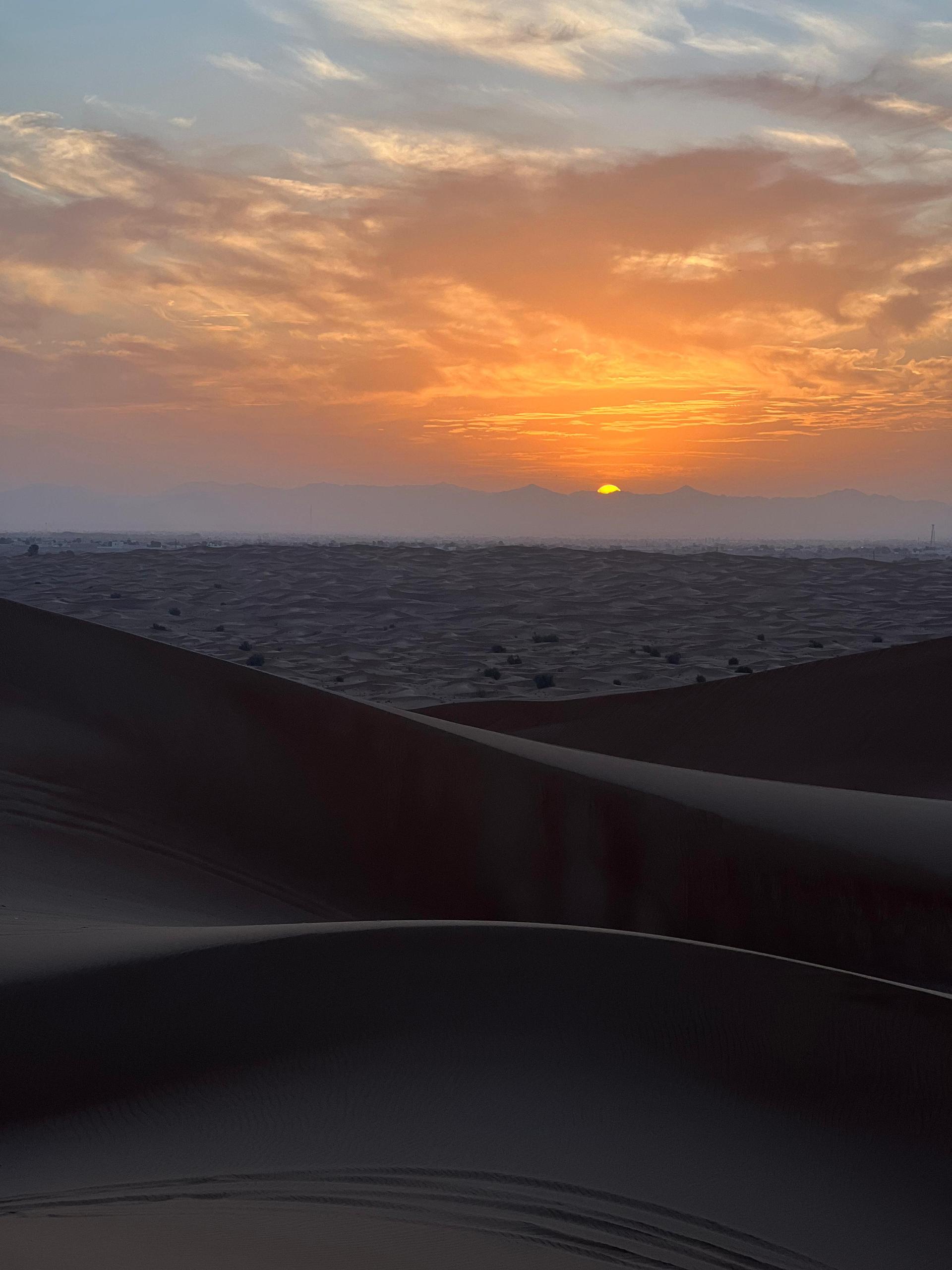 Tourist watching sunrise over Dubai desert dunes