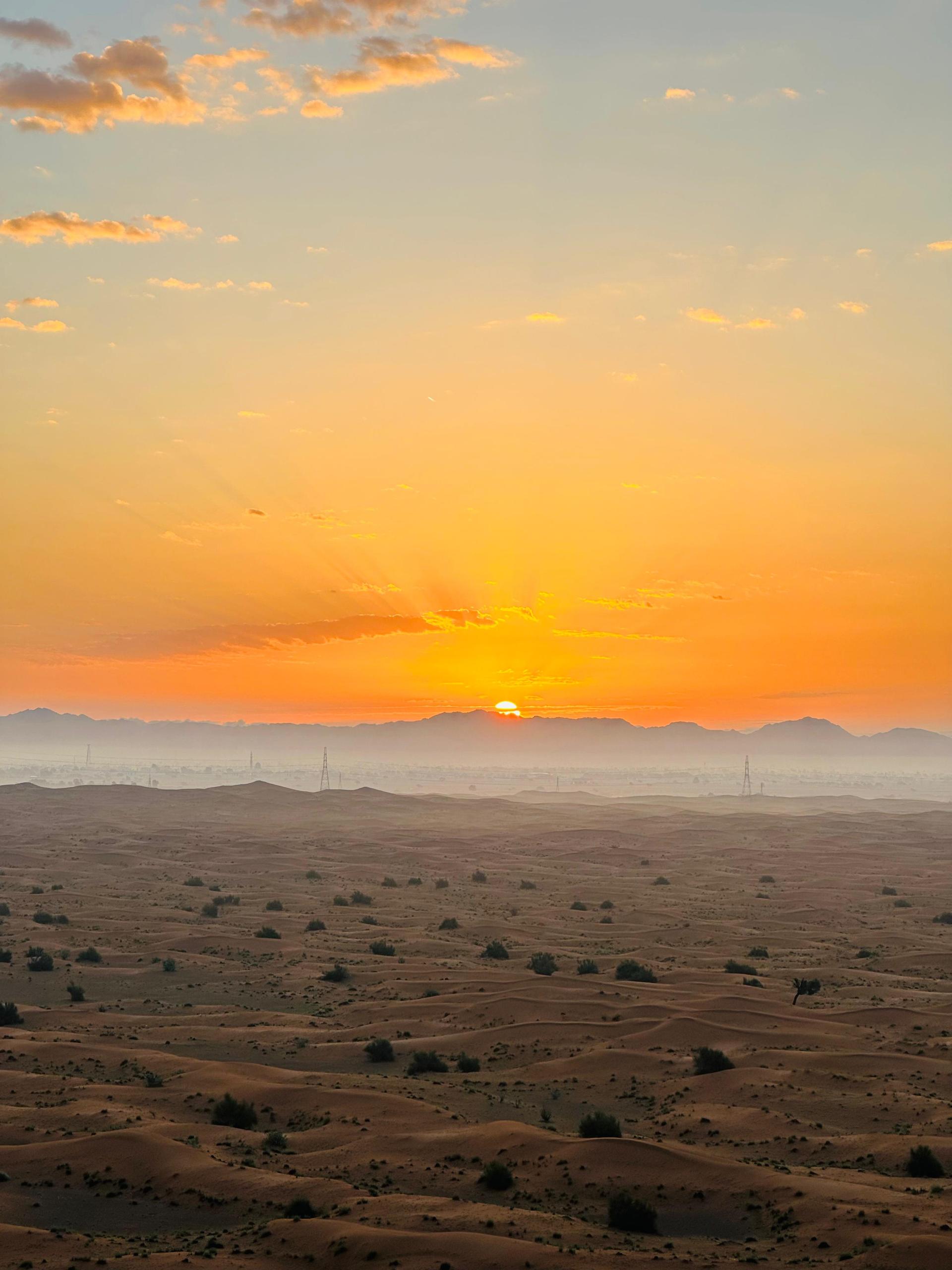 Sun rising over red sand dunes at Lahbab desert Dubai