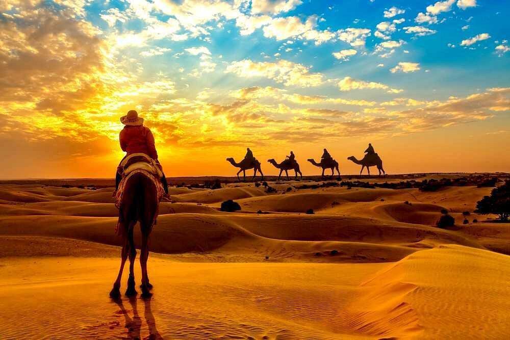 Tourists walking across red sand dunes during morning safari Dubai