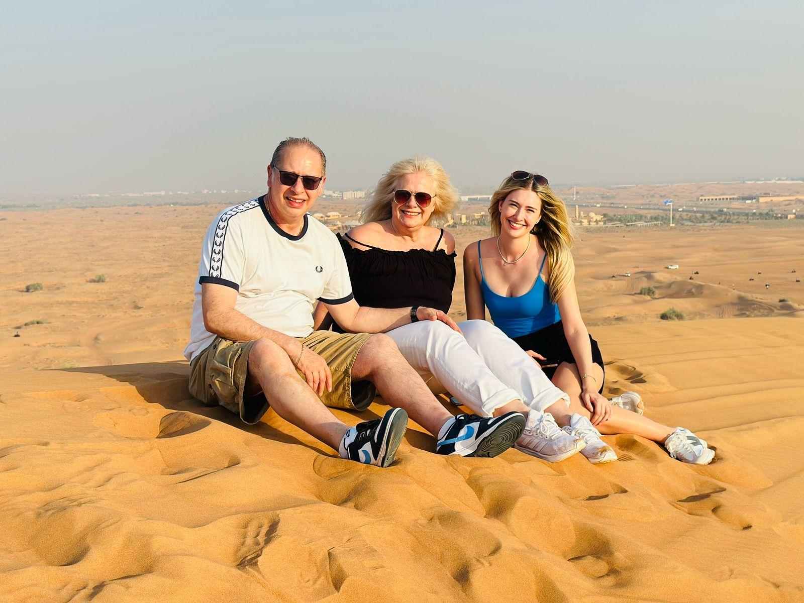 Couple sitting on sand dunes during morning desert safari Dubai