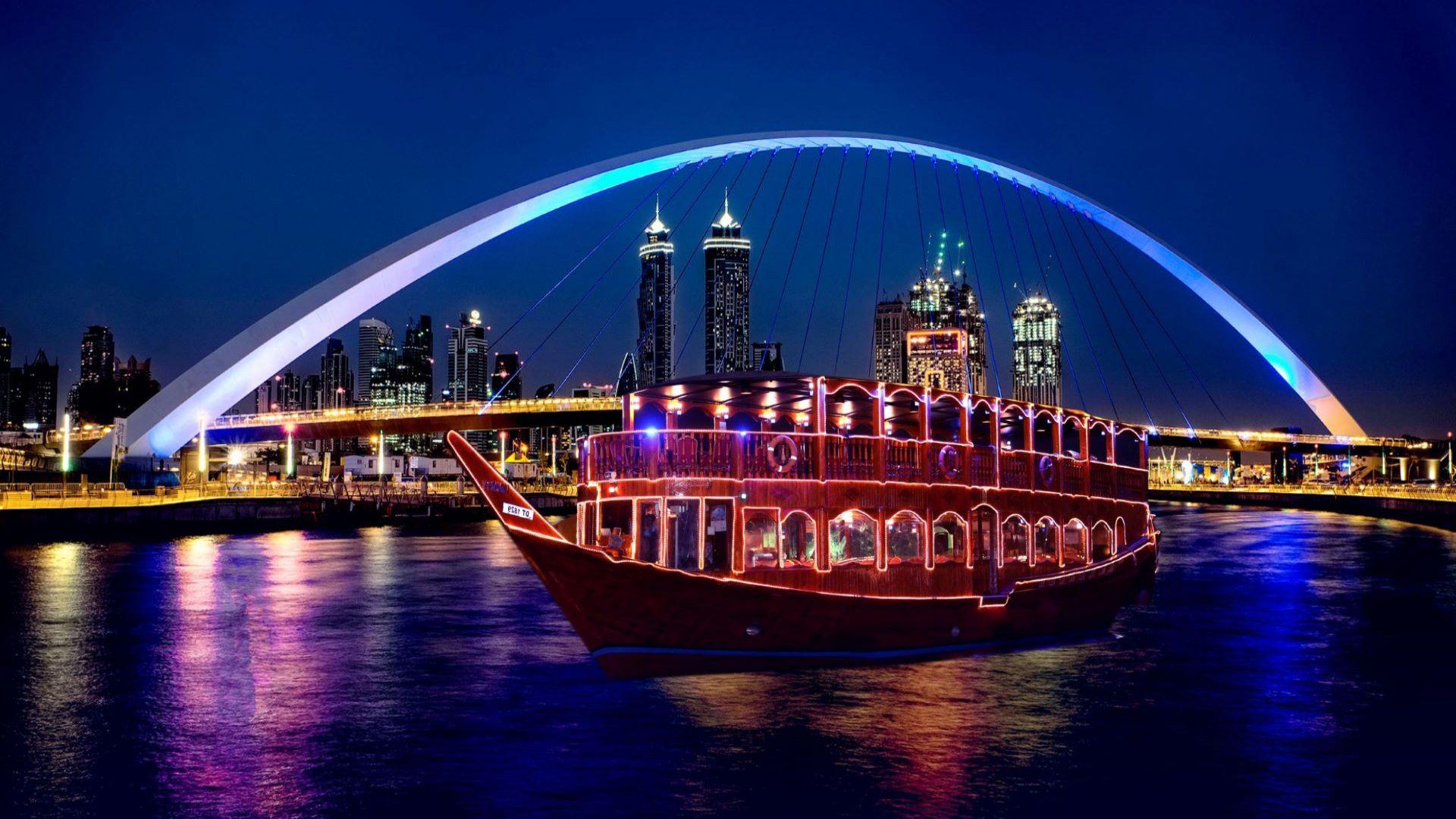 Blue illuminated bridge over Dubai Marina during evening dhow cruise