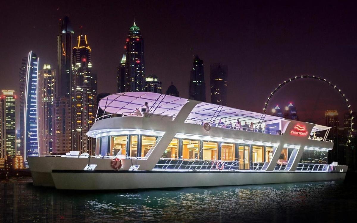 Celeste cruise boat lit up at night with Ain Dubai ferris wheel in background