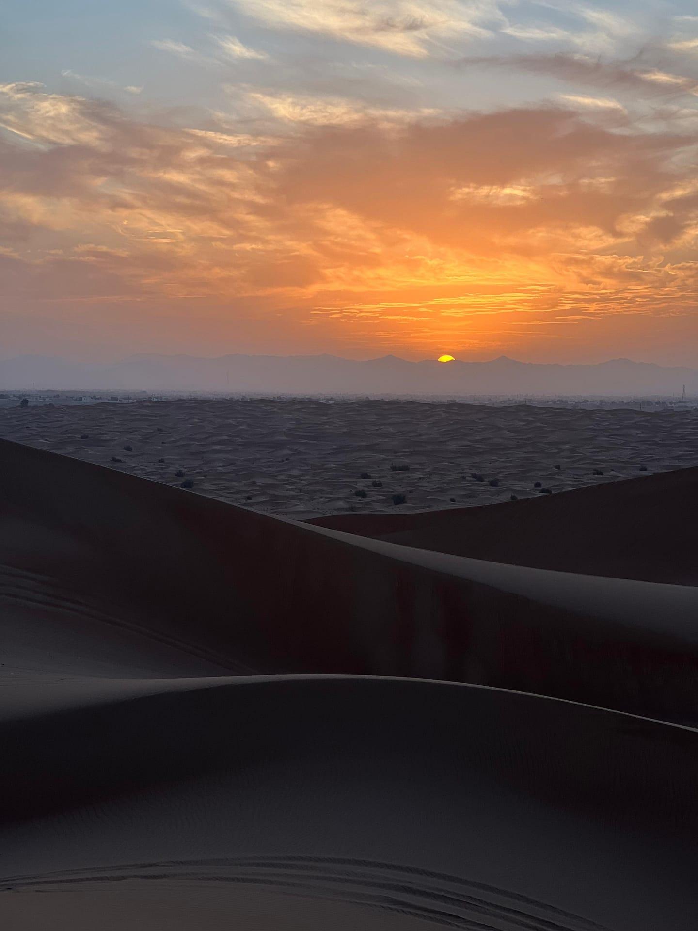 Tourist watching sunrise over Dubai desert dunes