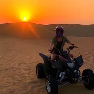 Rider on quad bike at sunset during red dune adventure Dubai